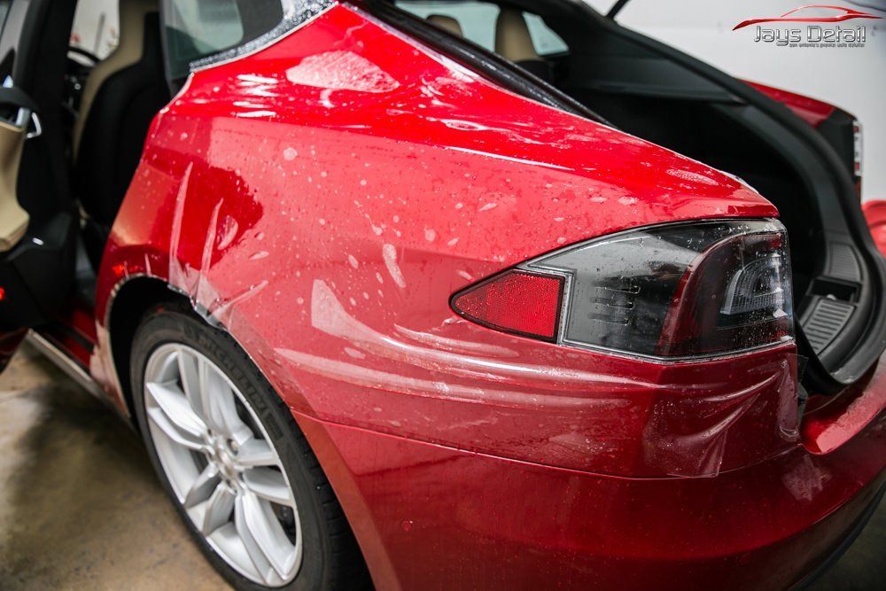 Red Tesla Model S rear quarter panel with protective film applied.