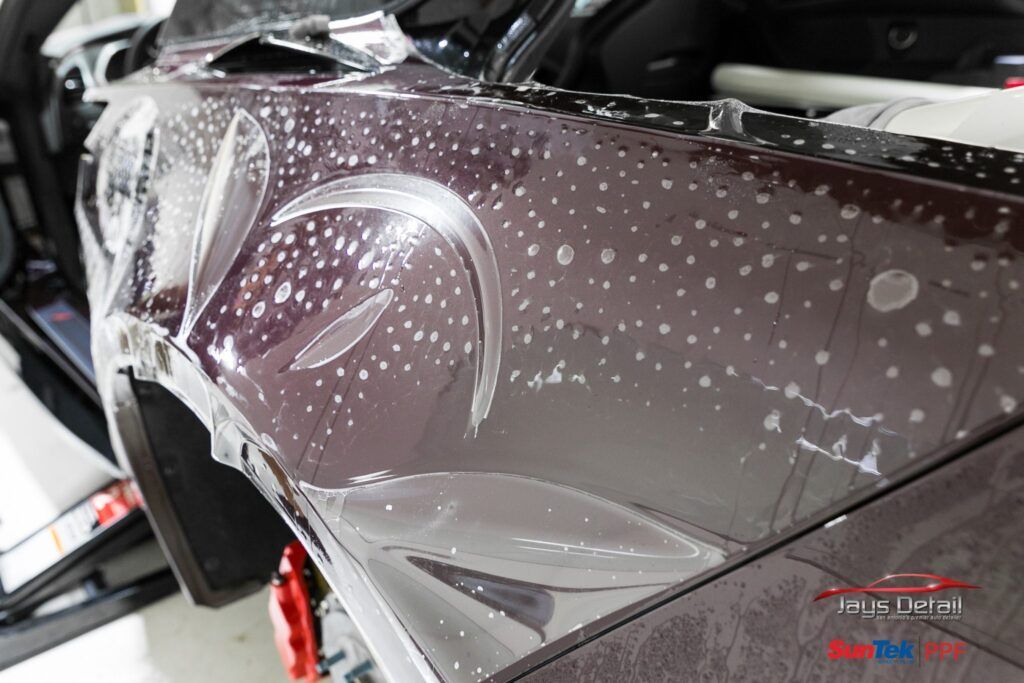 Car fender with clear paint protection film applied, showing bubbles.