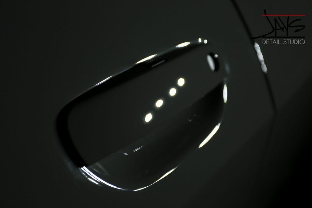 Black car side mirror reflecting bright lights.