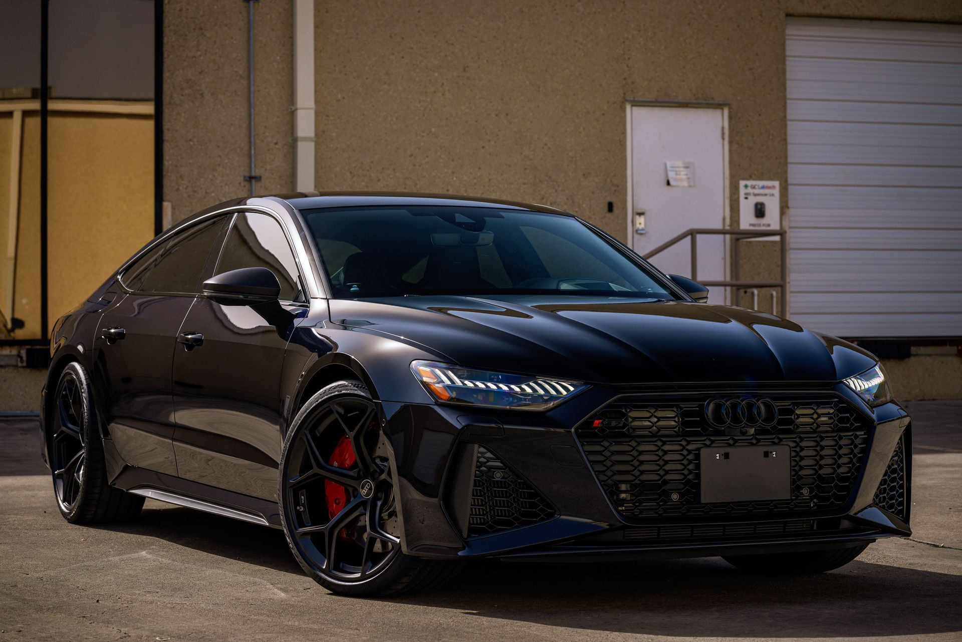 Black Audi RS7 sports car parked outside a building.