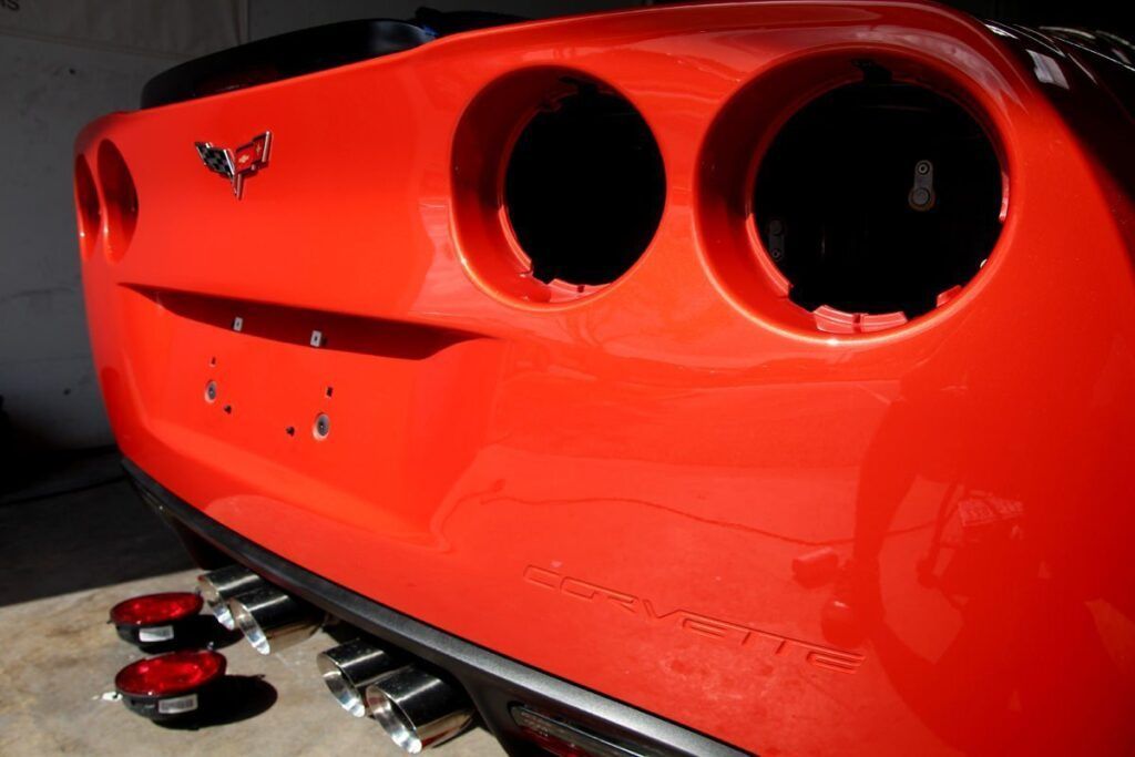 Red Corvette rear with tail light holes, chrome exhaust tips, and removed tail lights.