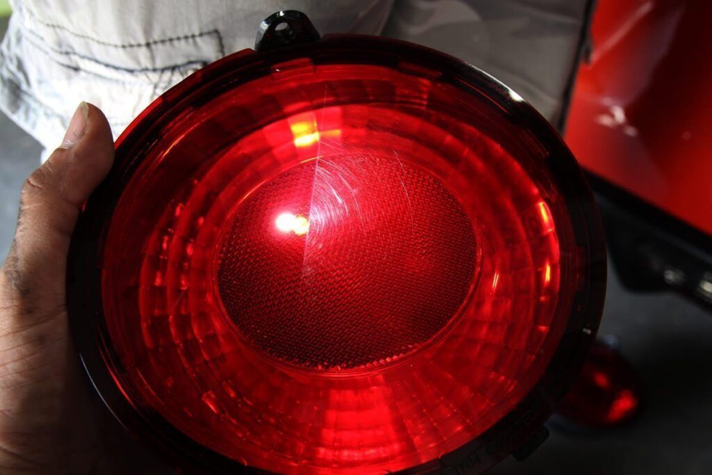 Red car taillight held in a hand, displaying circular design with bright lens.