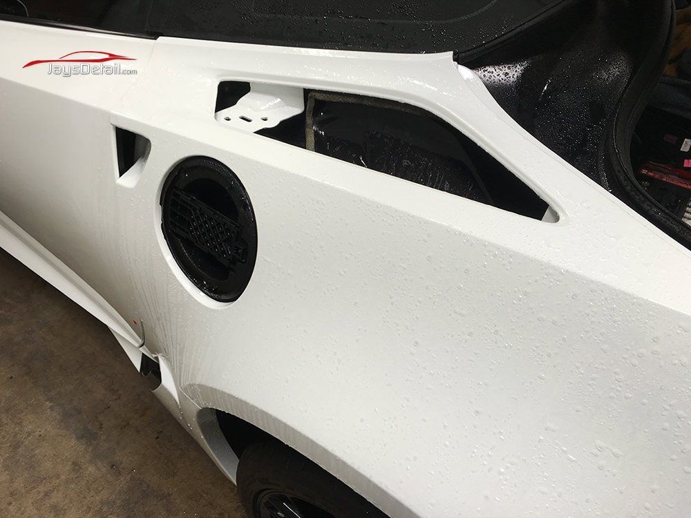 White car's rear quarter panel, with fuel door and air vent visible.