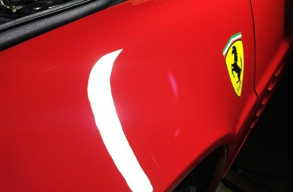 Red Ferrari car side with yellow shield logo.