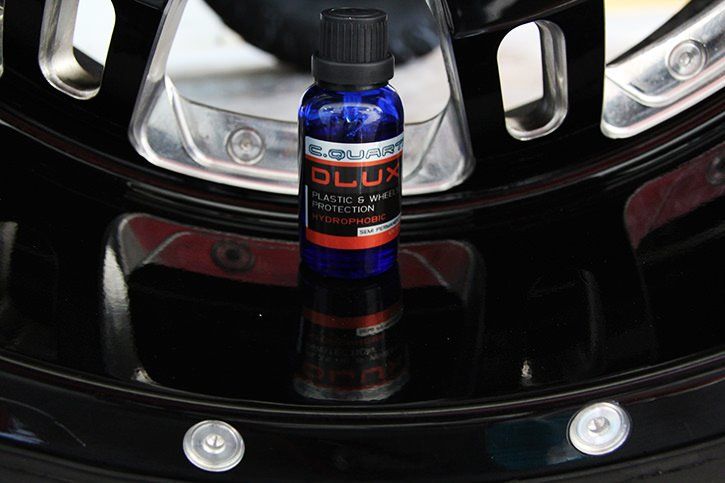 Blue bottle of car paint protection on a microfiber cloth on a black car.