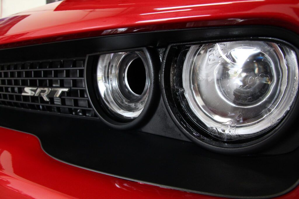 Close-up of a red Dodge Challenger front end, highlighting a black grill with