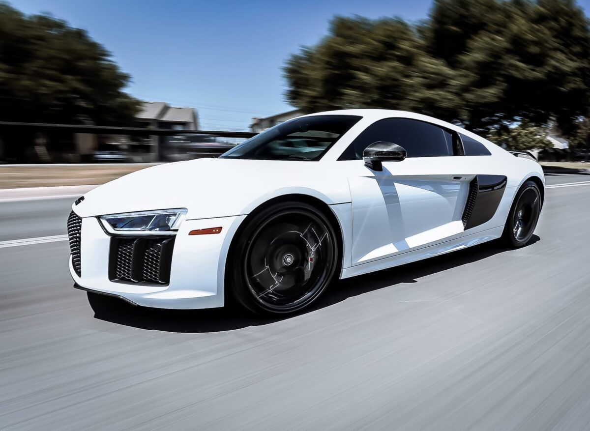White sports car speeding down a road, blurred background.