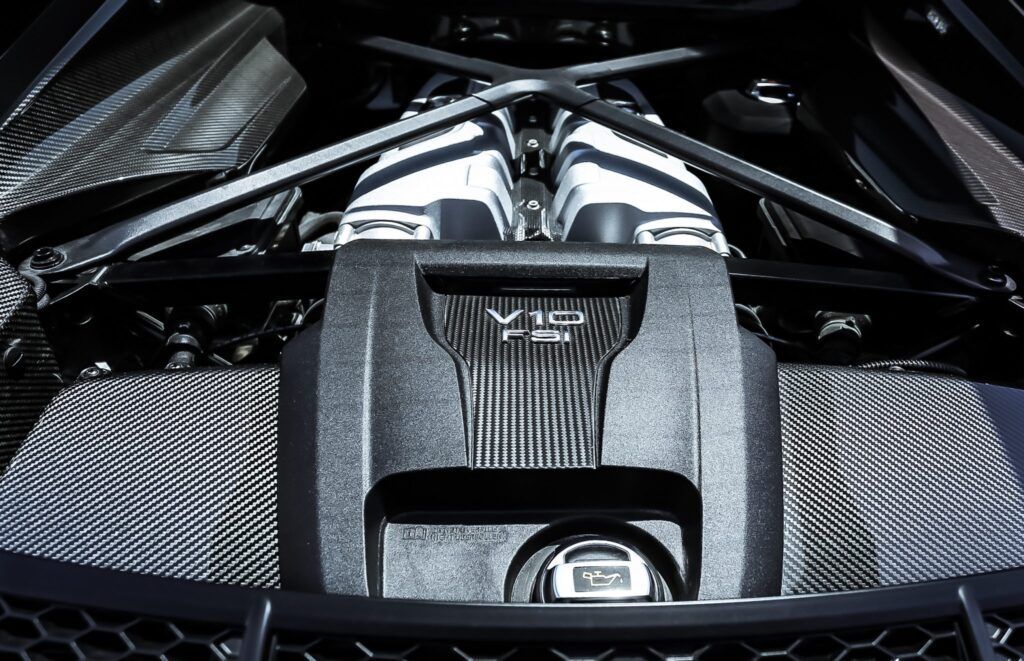 Black car engine with metal support beams and a dark cover.