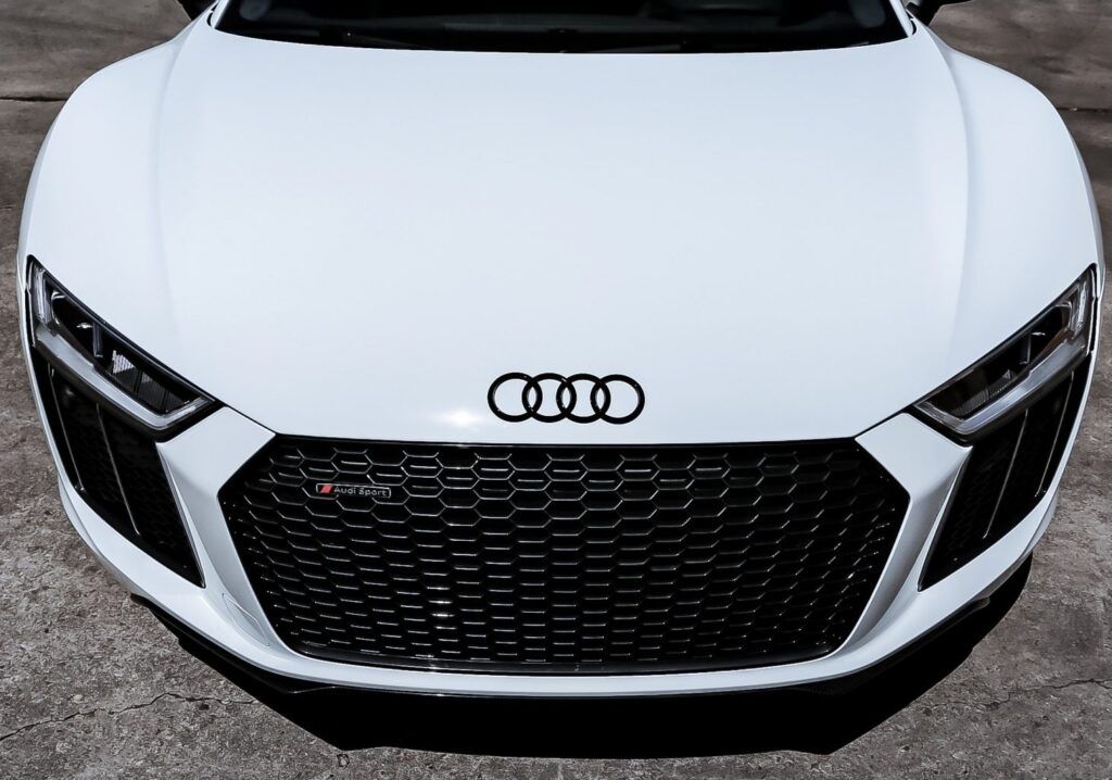 White Audi R8's front, top view: black grille, four rings logo.
