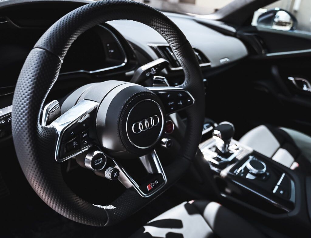 Black Audi R8 steering wheel, dashboard, and gear shift knob; sporty interior.