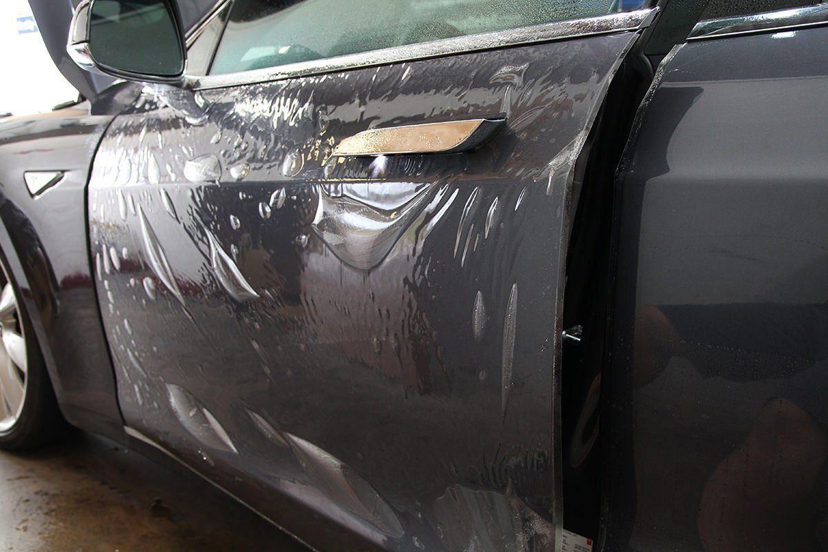 Dark gray car door with clear protective film applied.