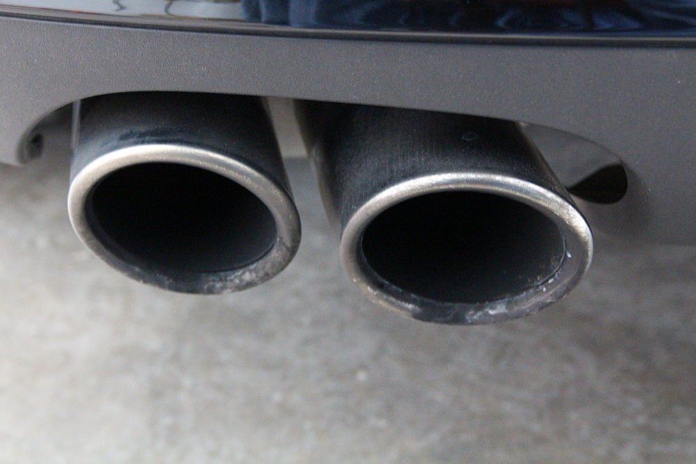 Dual exhaust pipes with chrome trim on a black car.