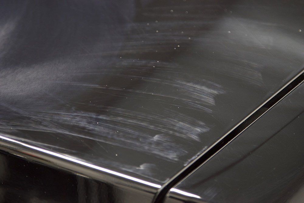 Black car surface with visible swirl marks after polishing.