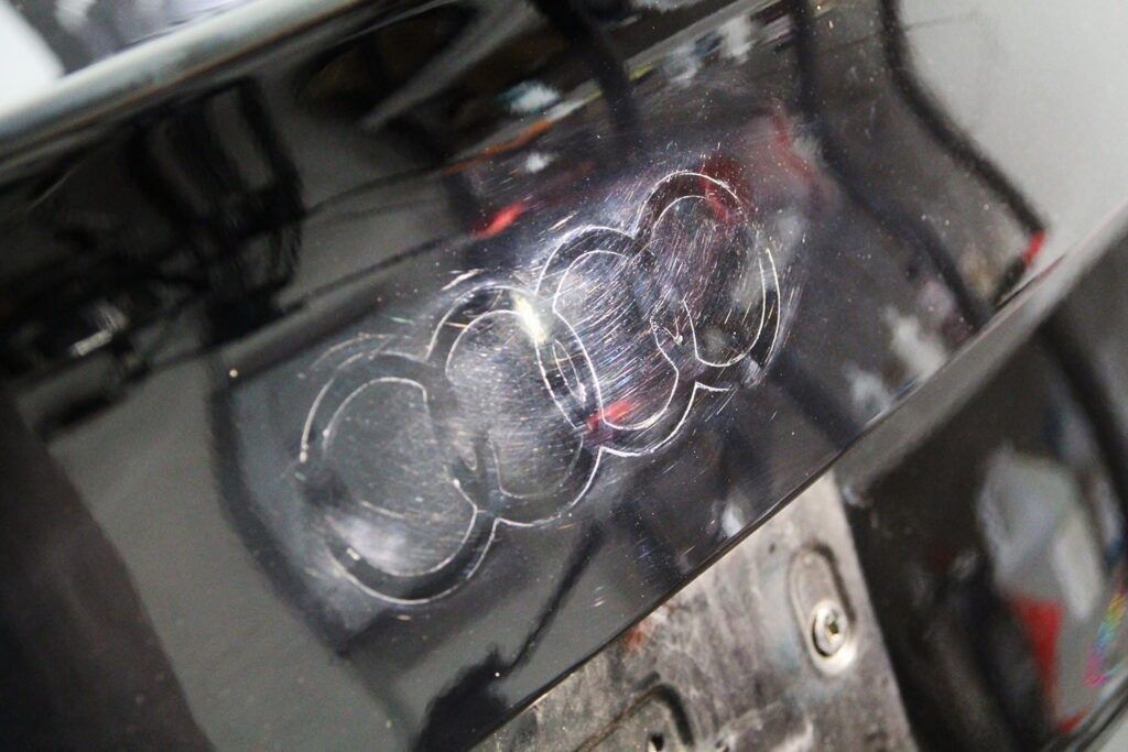 Audi emblem etched into the black paint of a car.