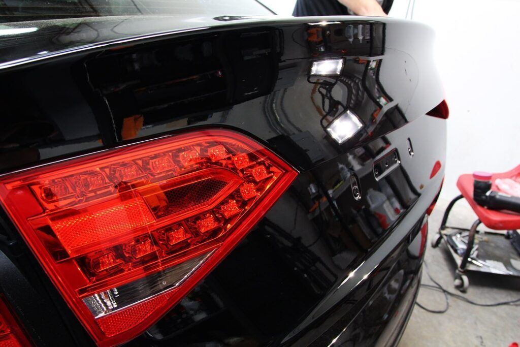 Close-up of a black car's taillight; red and black colors are dominant.