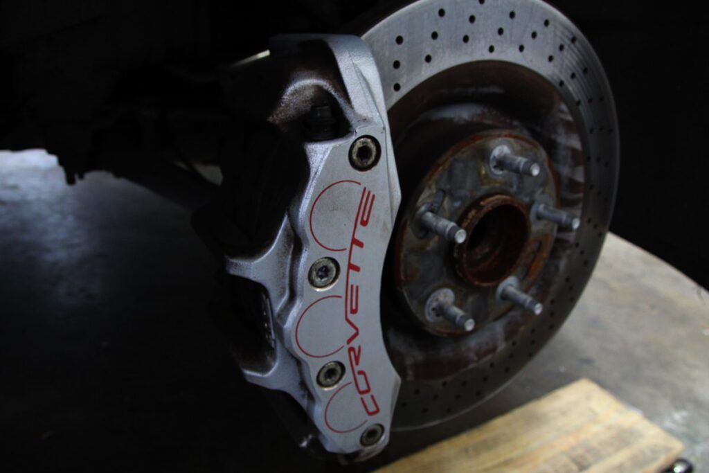 Close-up of a Corvette brake assembly with a silver caliper, slotted rotor, and red