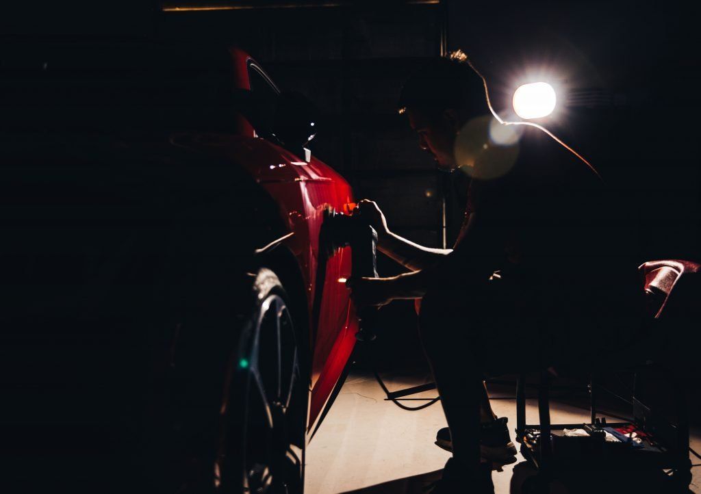 Red motorcycle illuminated in a dark garage. A bright overhead light shines on the bike.