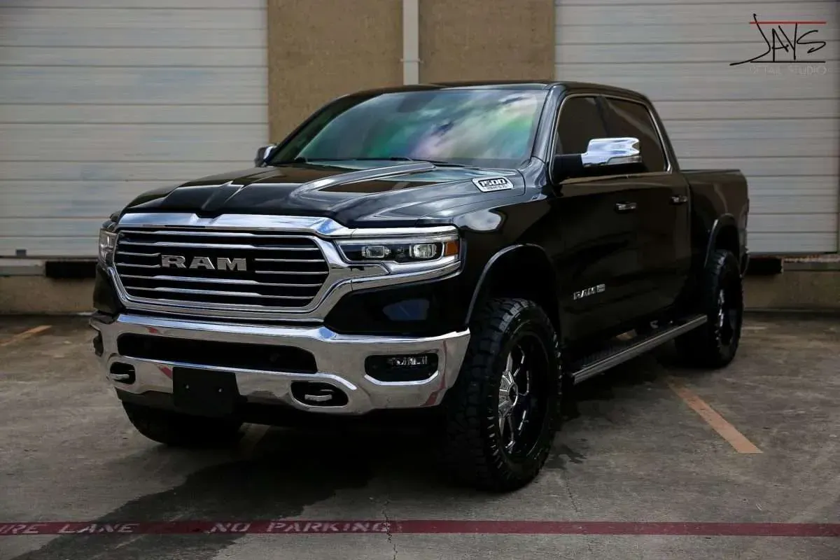 Black Ram pickup truck parked in front of a building with a silver grille and black wheels.