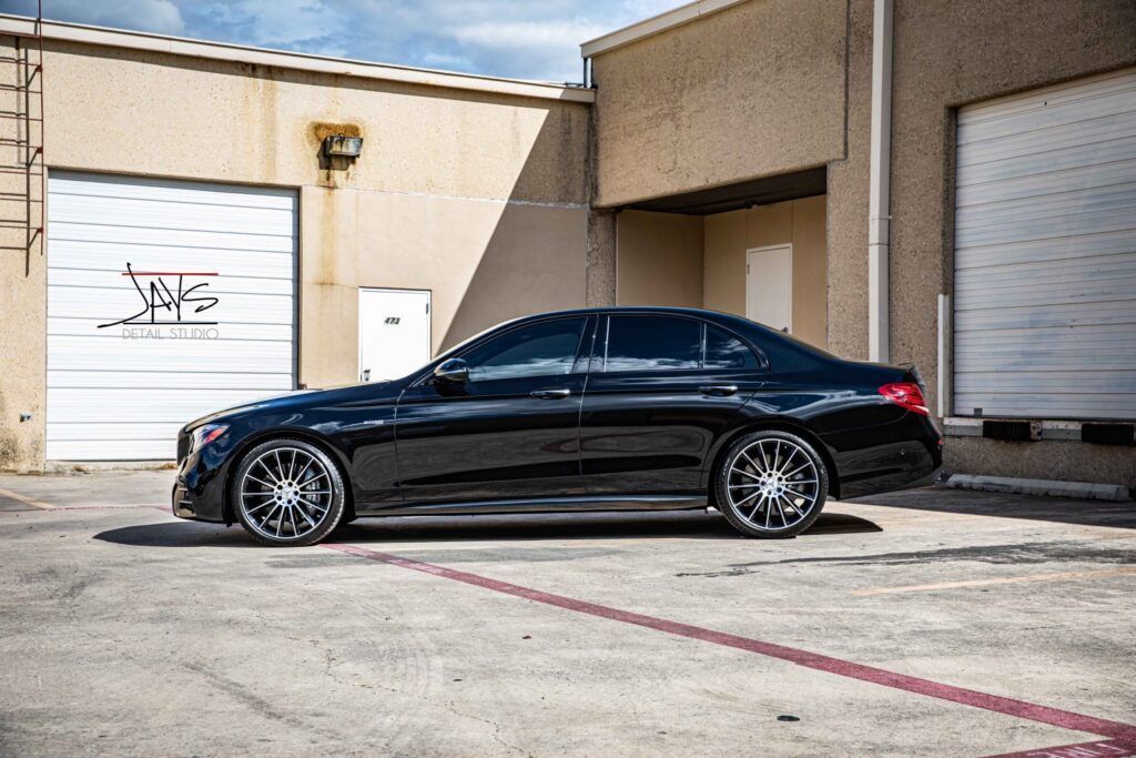 Black sedan parked outside a building with white garage doors.