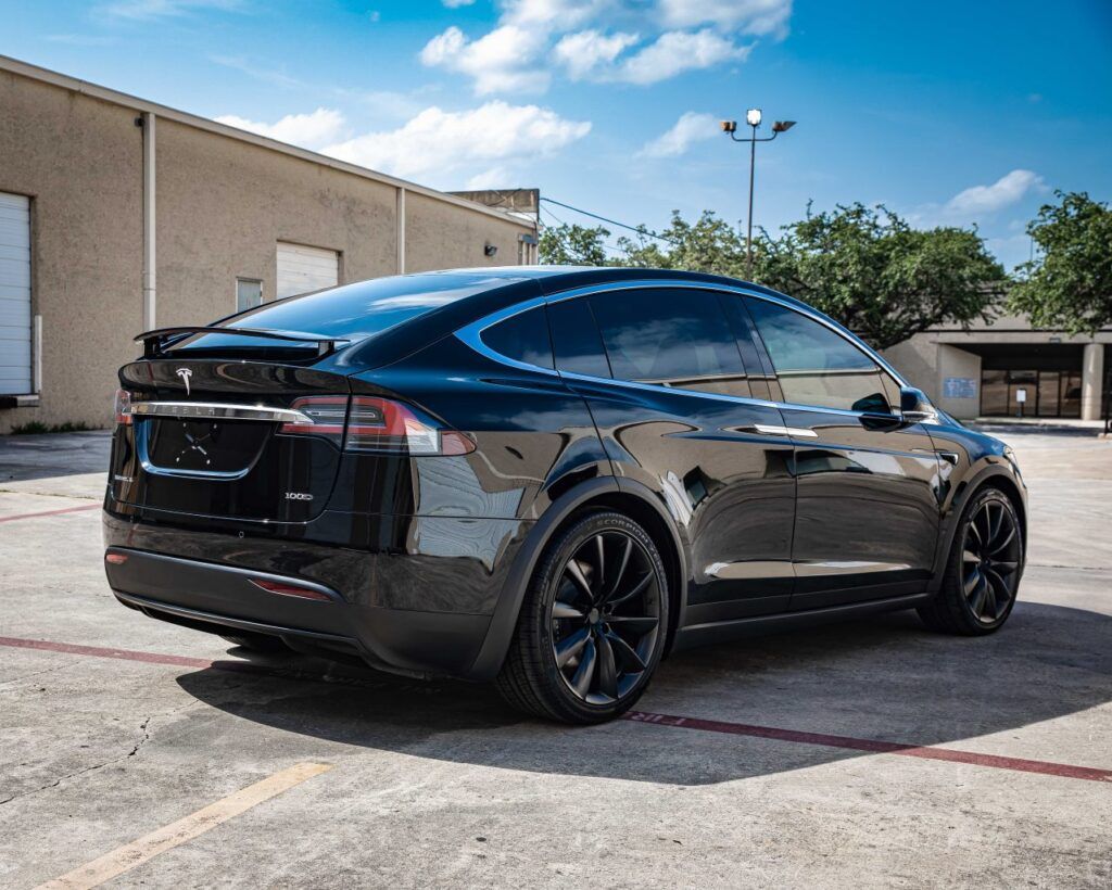 Black Tesla Model X SUV parked outside on a sunny day.