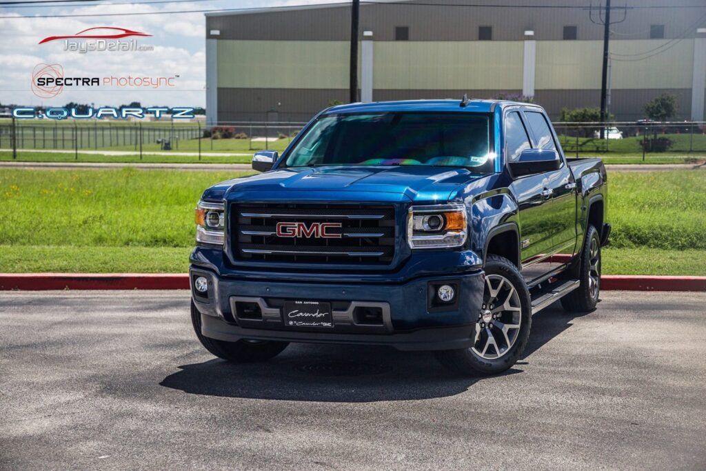 Blue GMC Sierra pickup truck parked on asphalt.