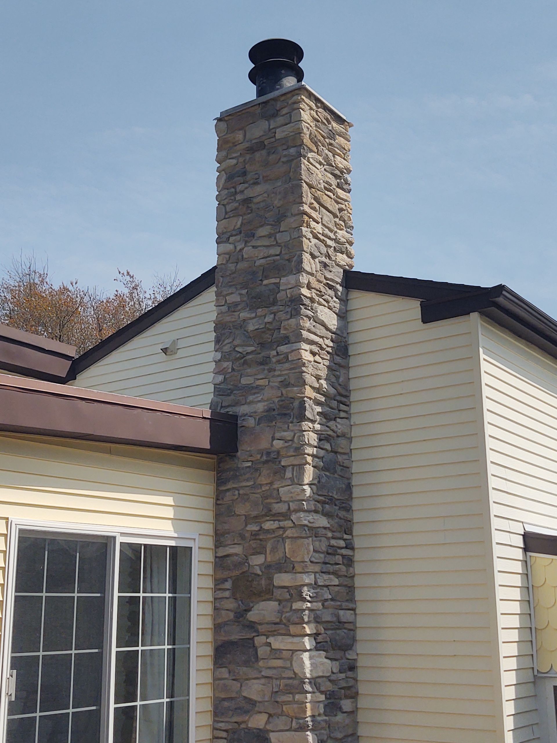 A large stone chimney on the side of a house