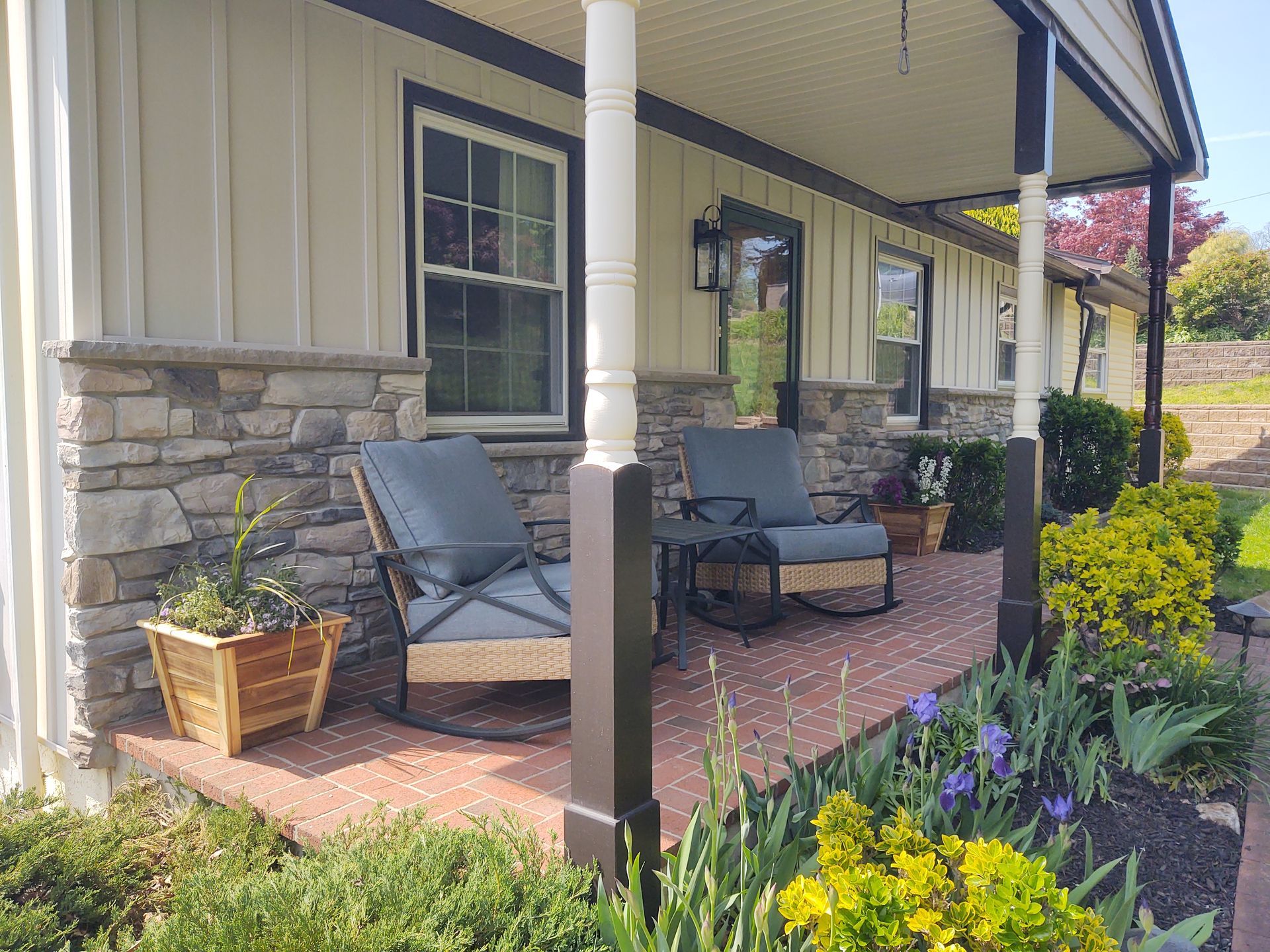 A porch with rocking chairs and a table in front of a house.