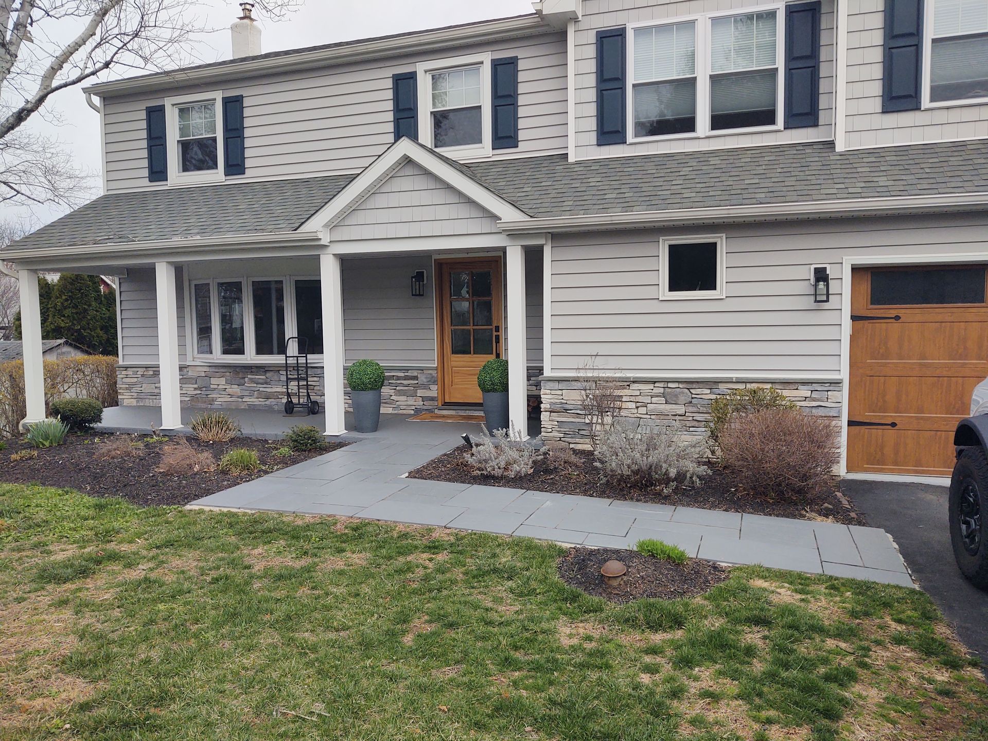 A house with a porch and a car parked in front of it.