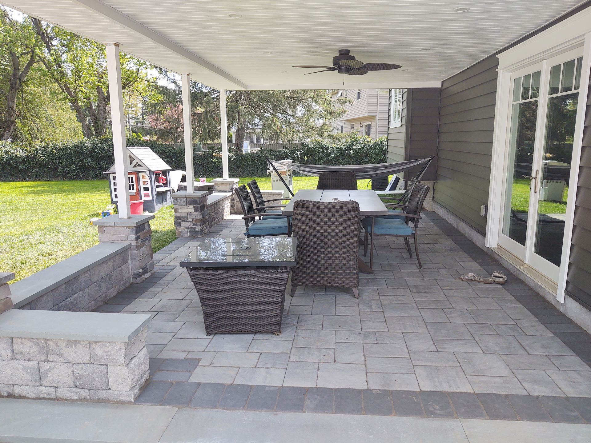 A patio with a table and chairs and a ceiling fan.