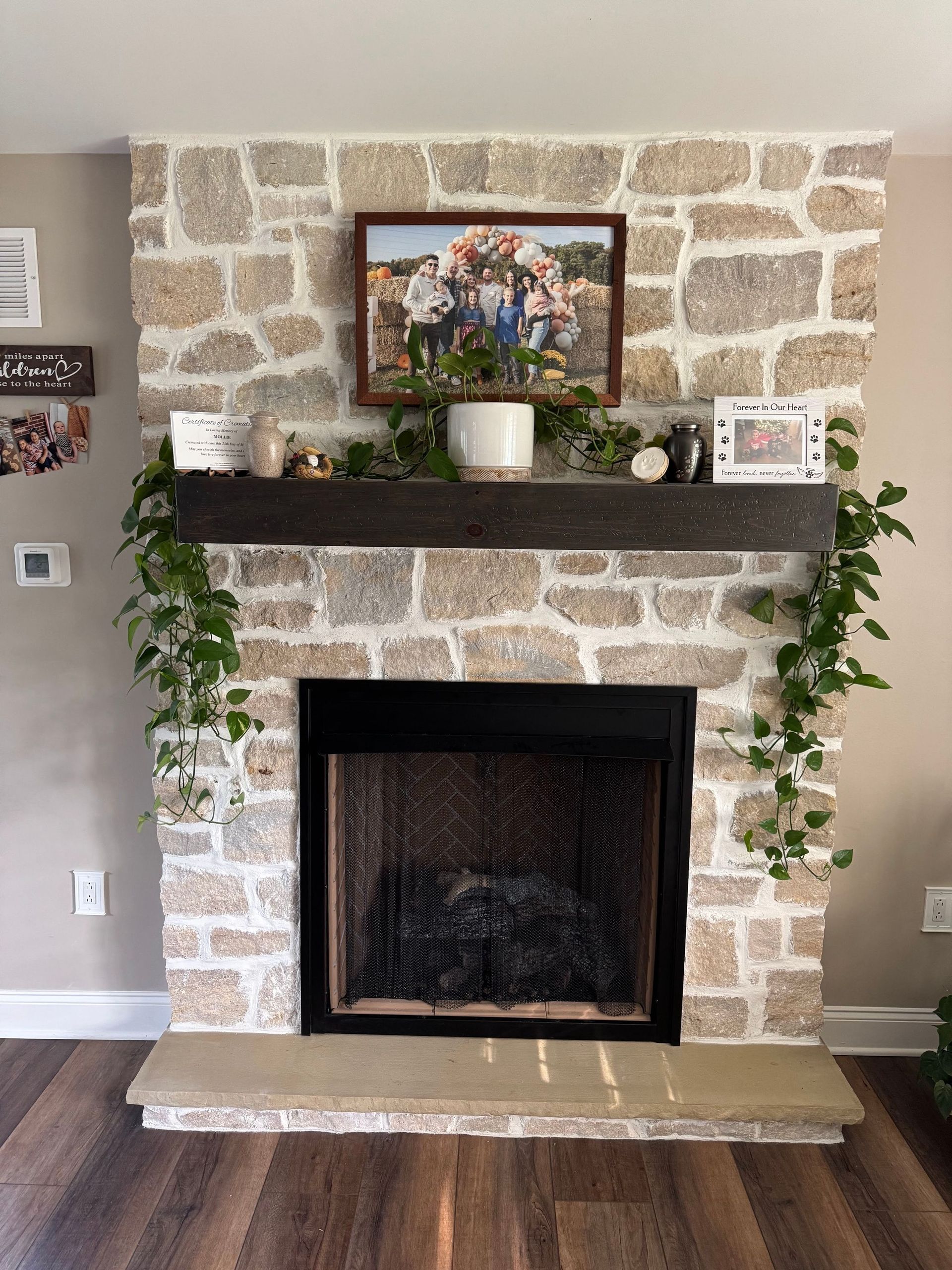 A living room with a stone fireplace and a picture on the mantle.