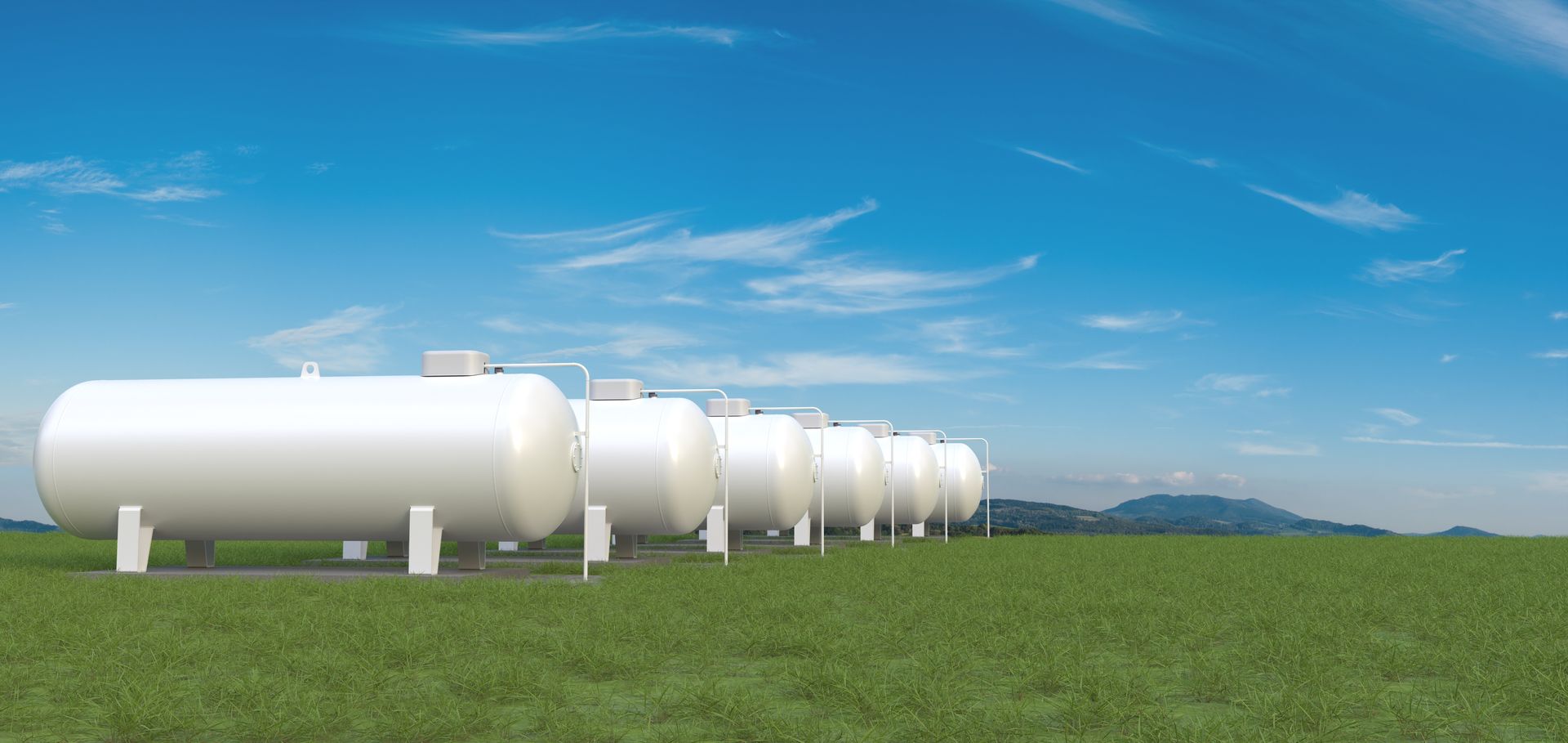 Row of big gas tanks in summer landscape.