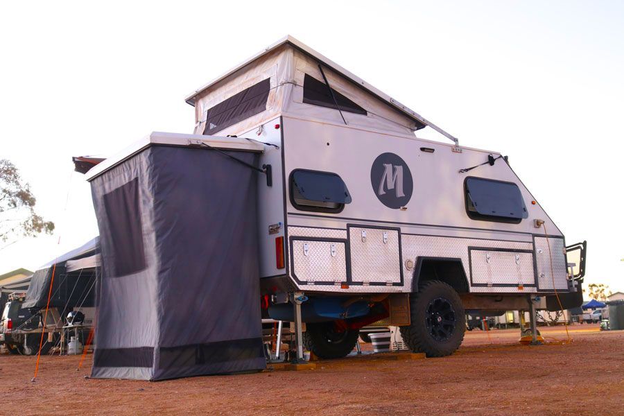 a white trailer with the letter m on the side is parked in a dirt field - Quality Camper Trailers For Sale In Townsville