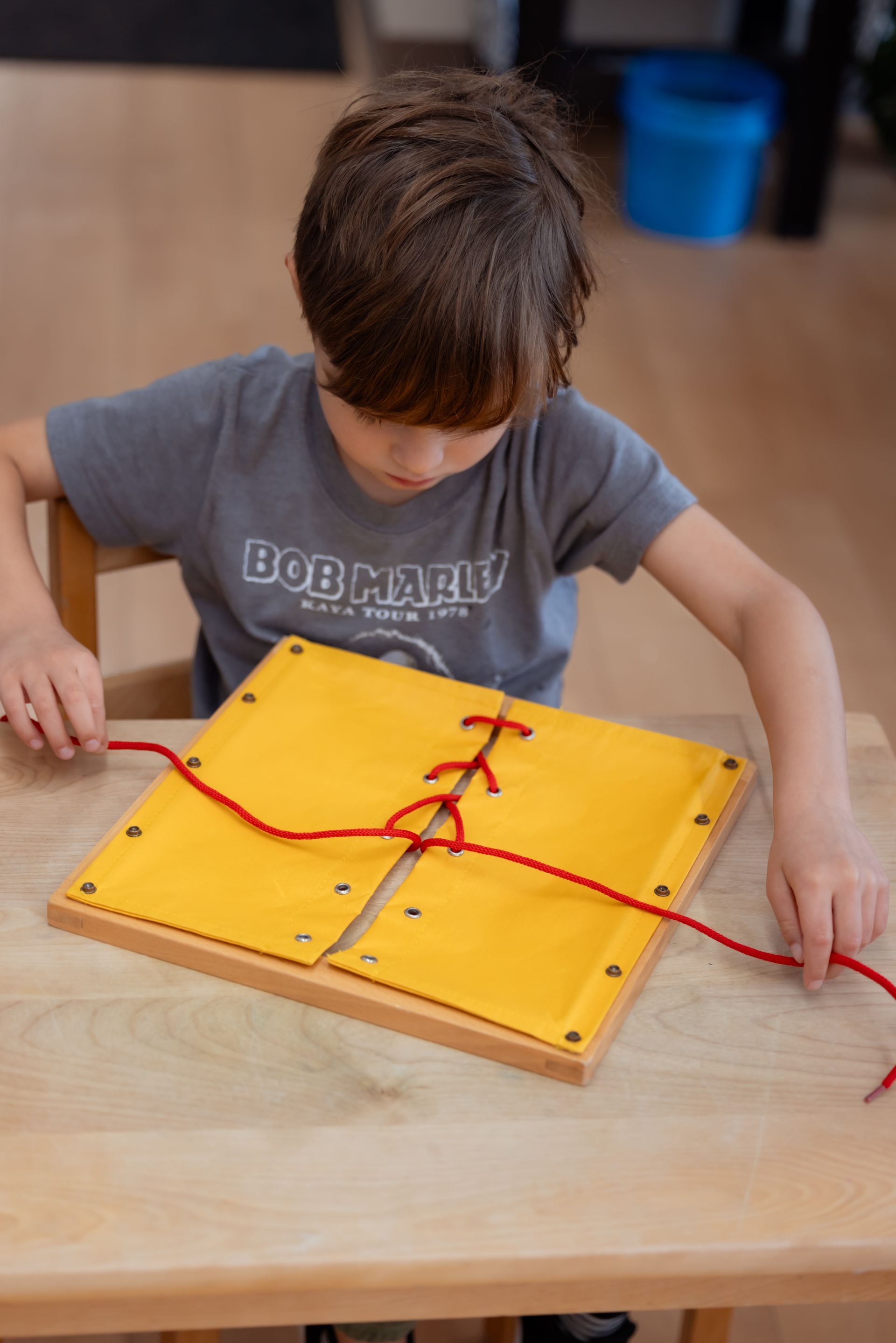 Child working with the Montessori tying frame material