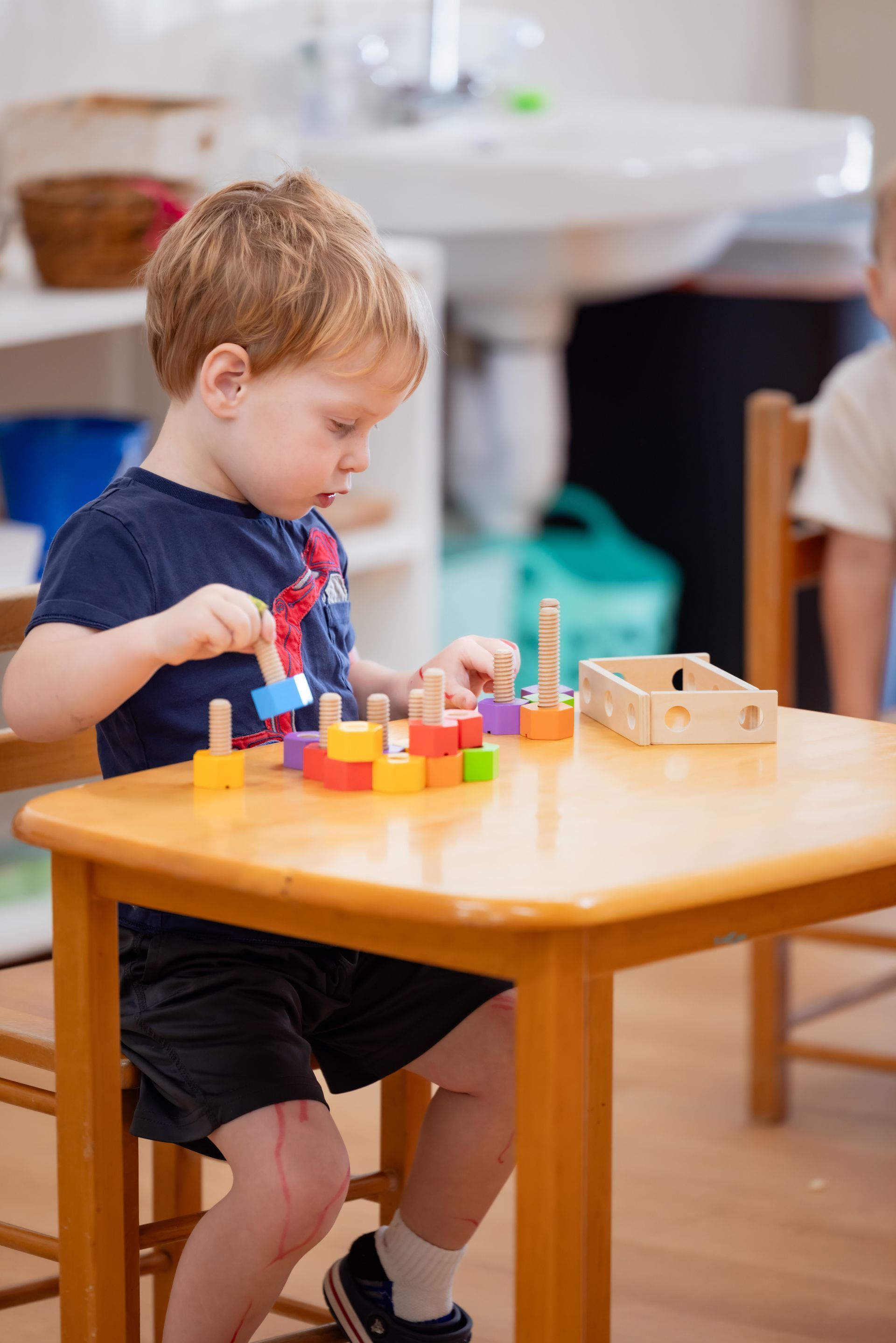 Montessori toddler working with wooden screws