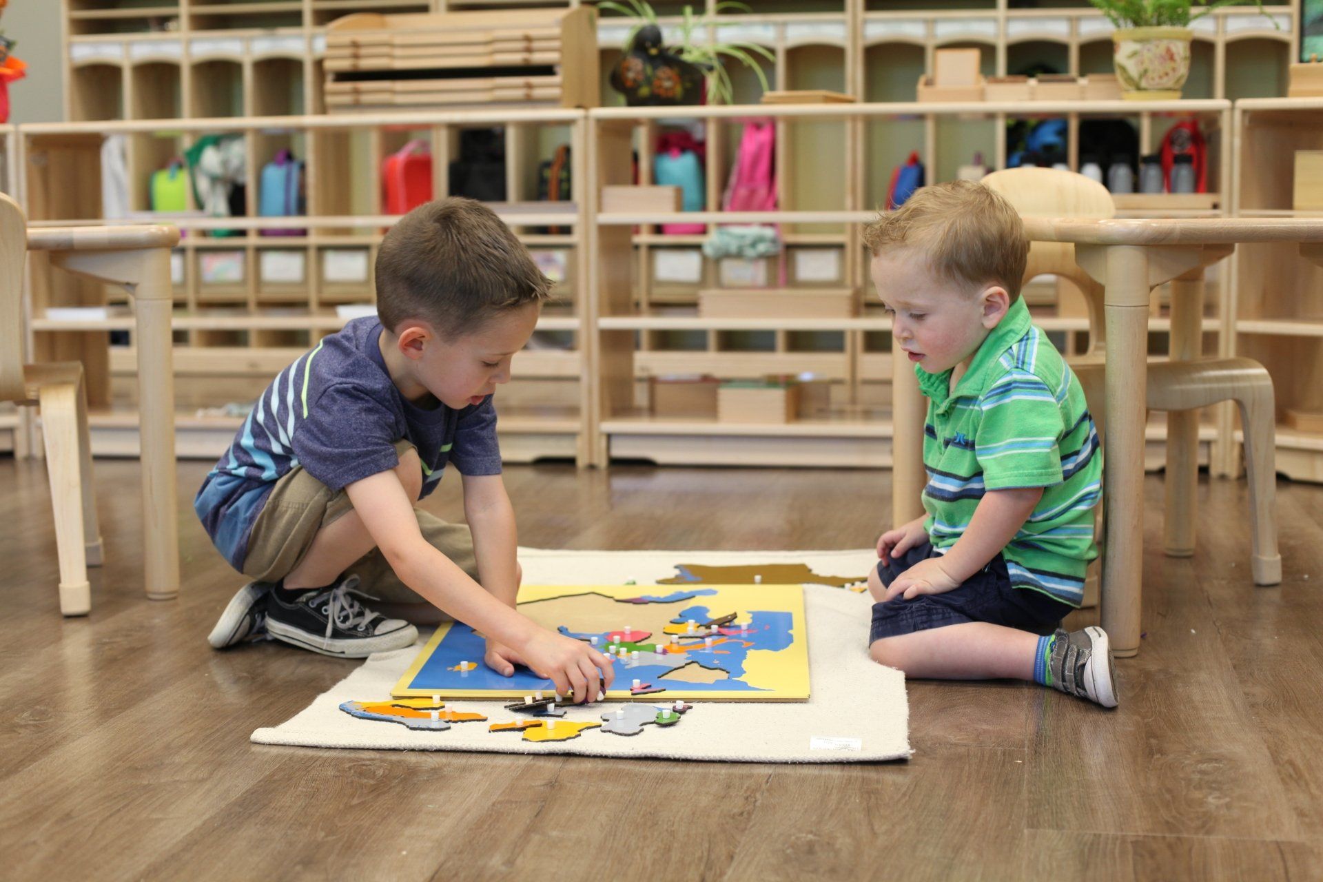 Montessori children working together with a map puzzle