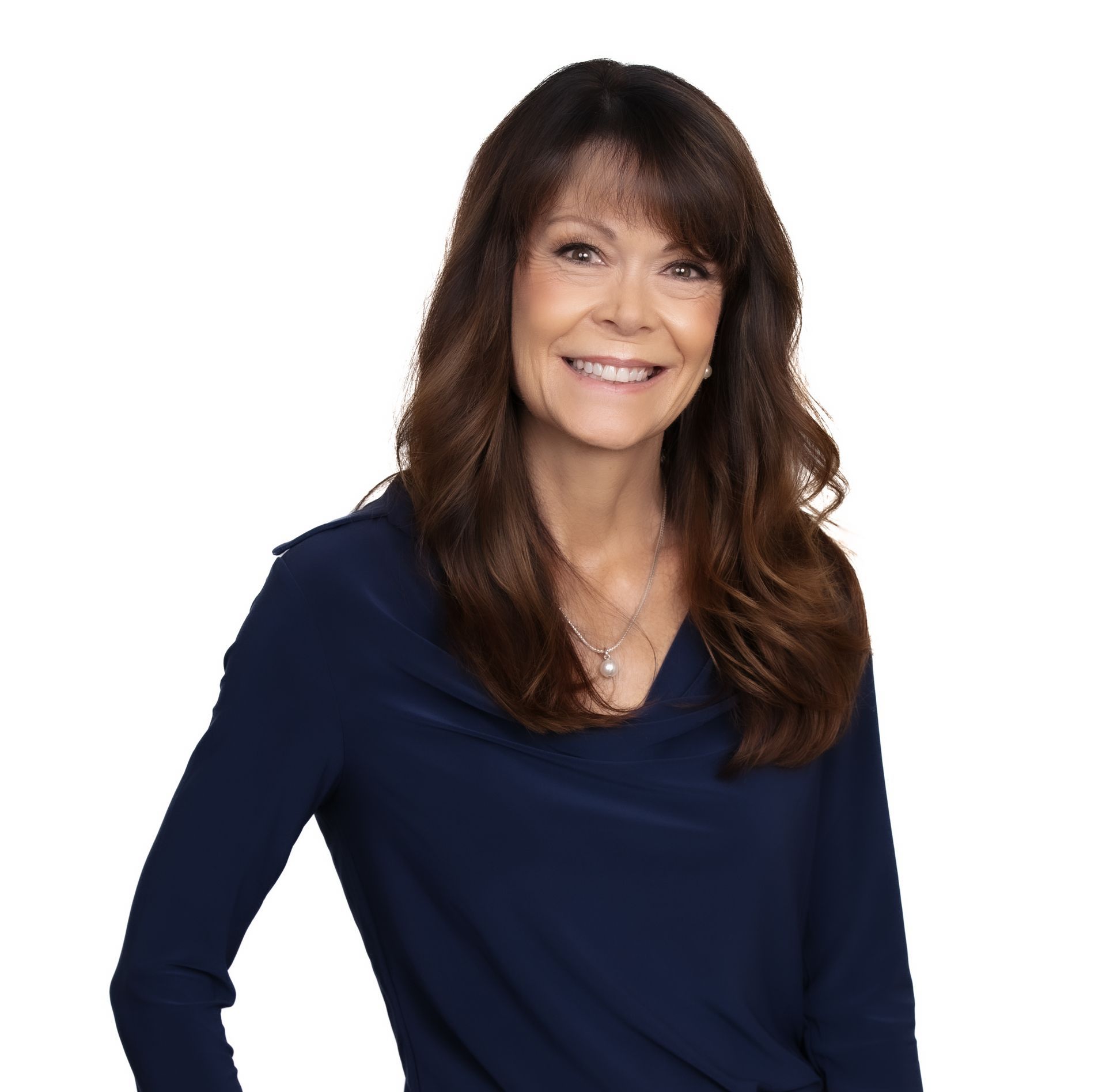 A woman is sitting at a table writing in a notebook next to a laptop.