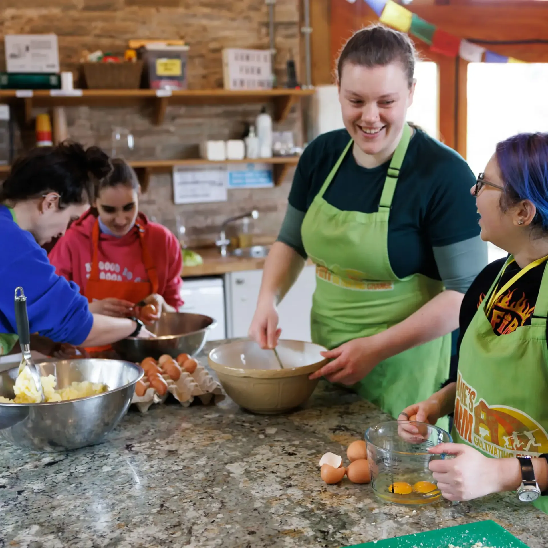 A group of people in green aprons are preparing food in a kitchen