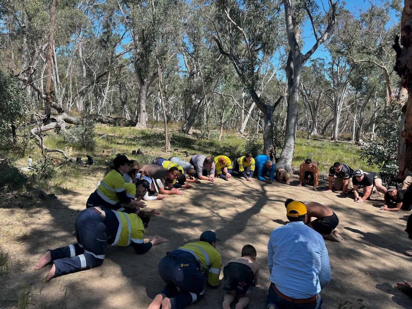 A Group of People in a Forest, Kneeling in a Circle, Some Wearing Work Clothes — Dinawans Connection in Cowra, NSW