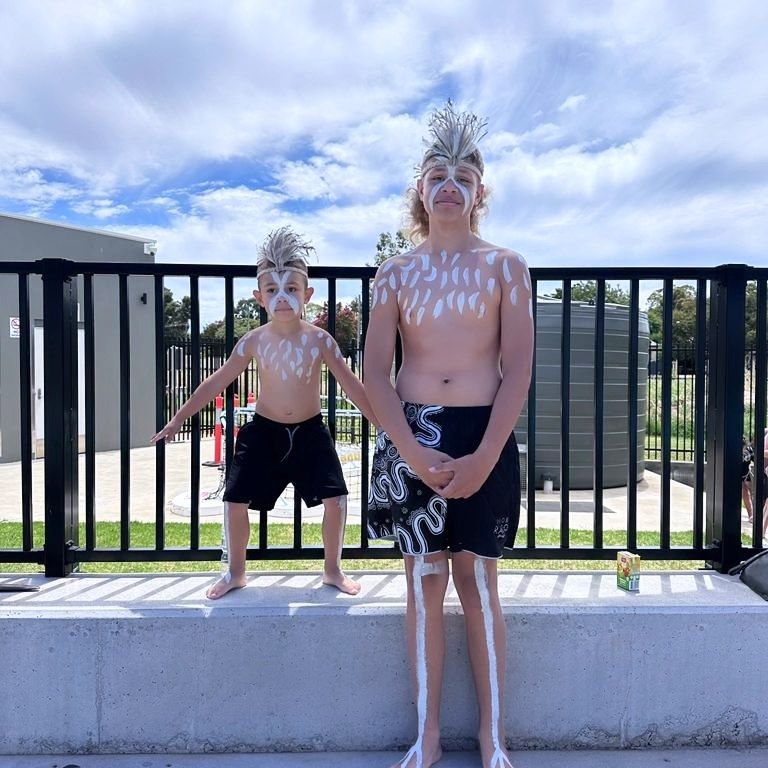 Two Boys With Body Paint and Headdresses Pose Outdoors Near a Fence — Dinawans Connection in Bathurst, NSW