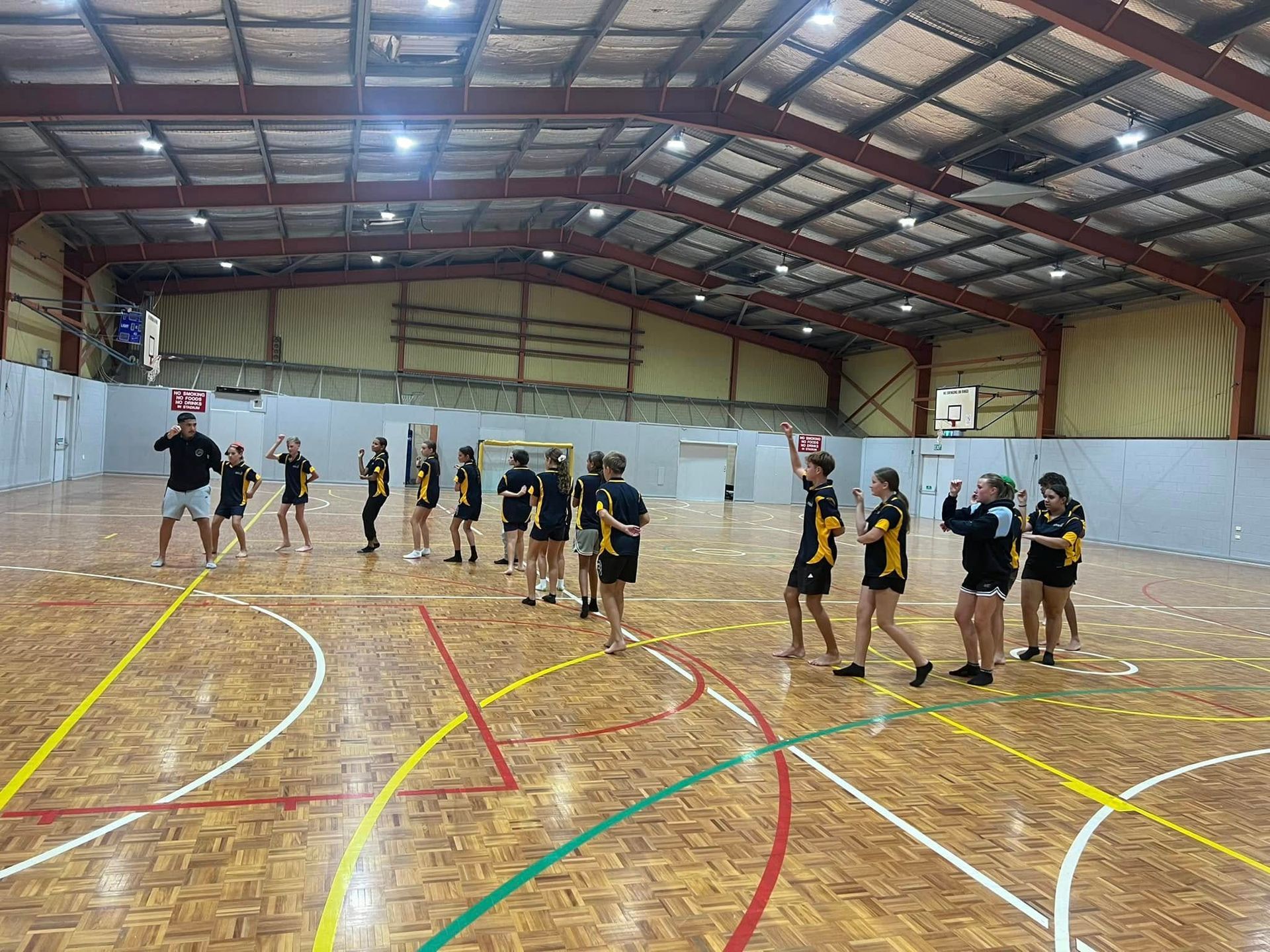 A Group of Teens in Yellow and Black Uniforms on a Wooden Court — Dinawans Connection in Mudgee, NSW