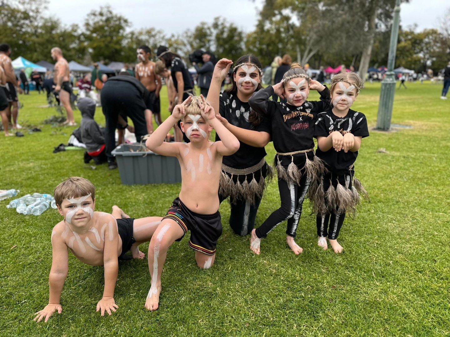 Children in Aboriginal Face Paint and Costumes Pose on Green Grass — Dinawans Connection in Cobar, NSW