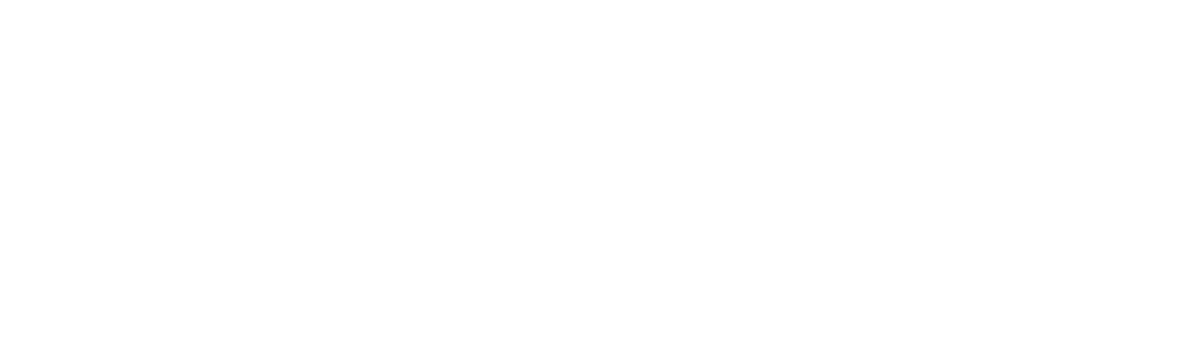 A group of diverse students sitting at desks in a brightly lit, modern classroom with large windows.