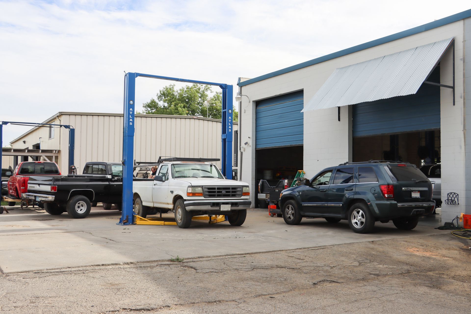 A truck is on a lift in front of a garage