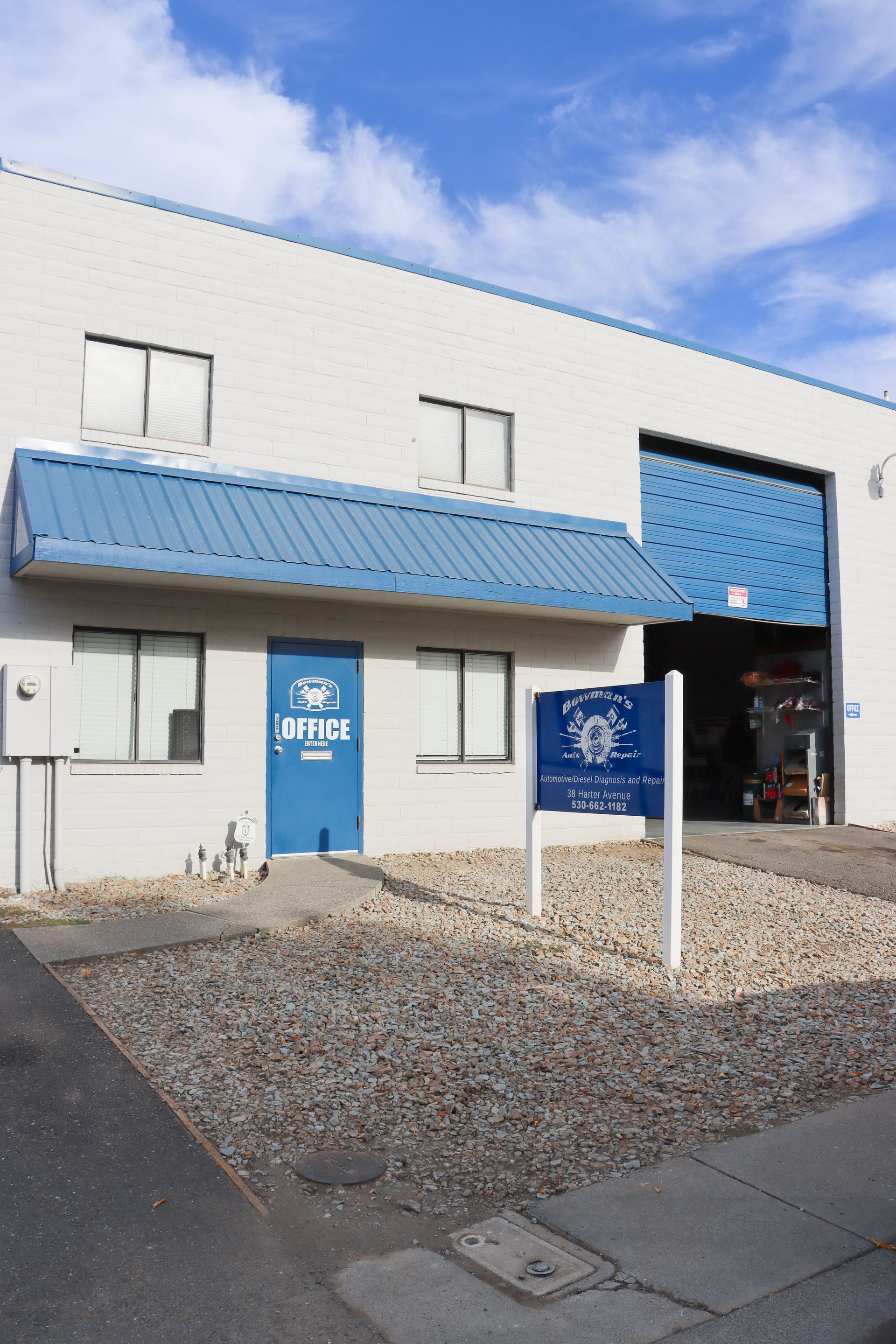 A white building with a blue roof and a sign in front of it