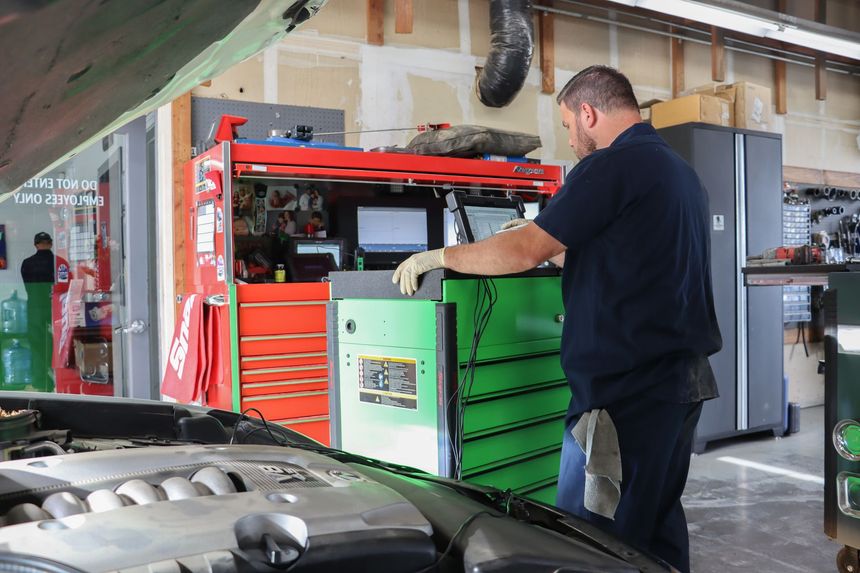 A man is working on a car engine in a garage.