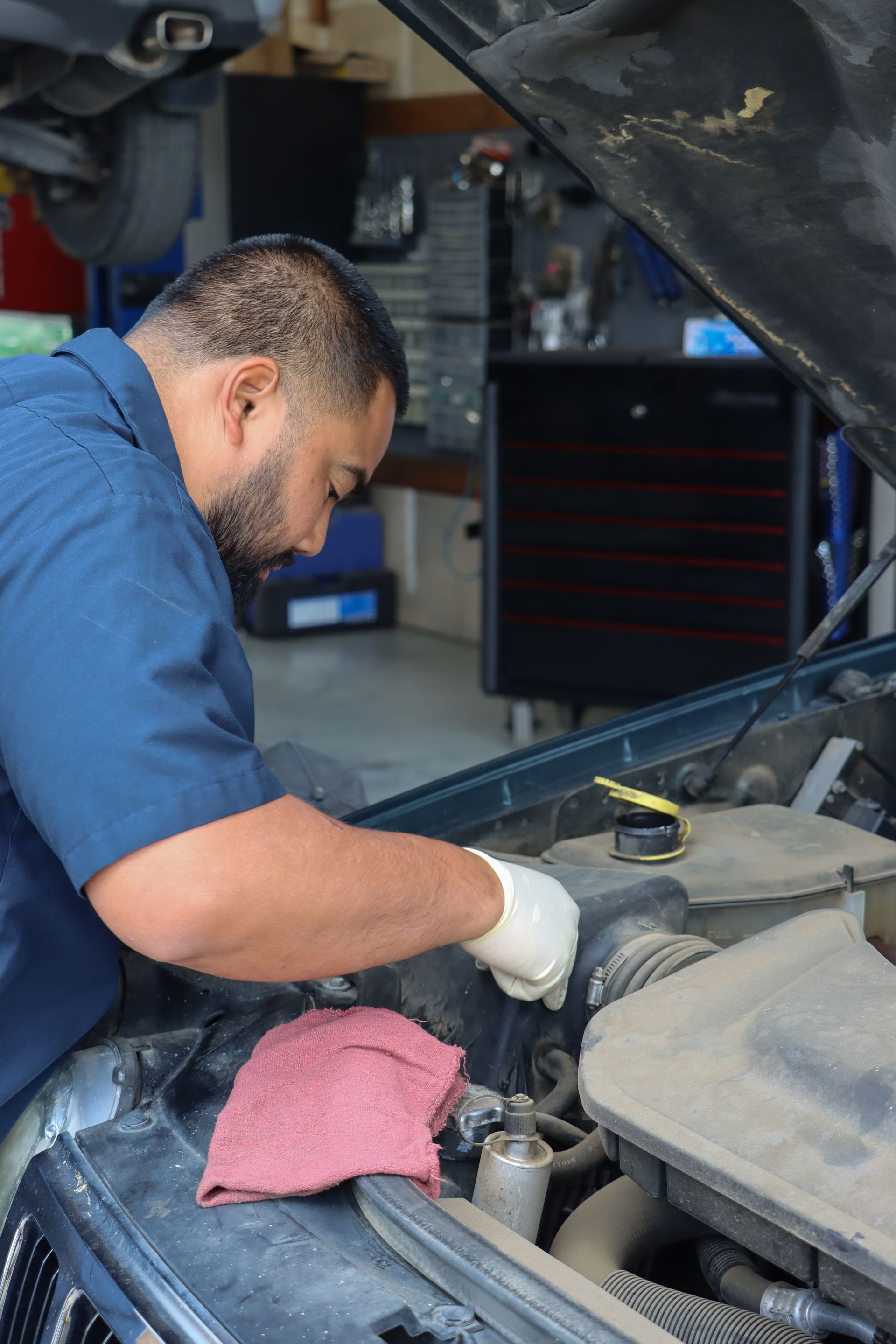 A man is working under the hood of a car.