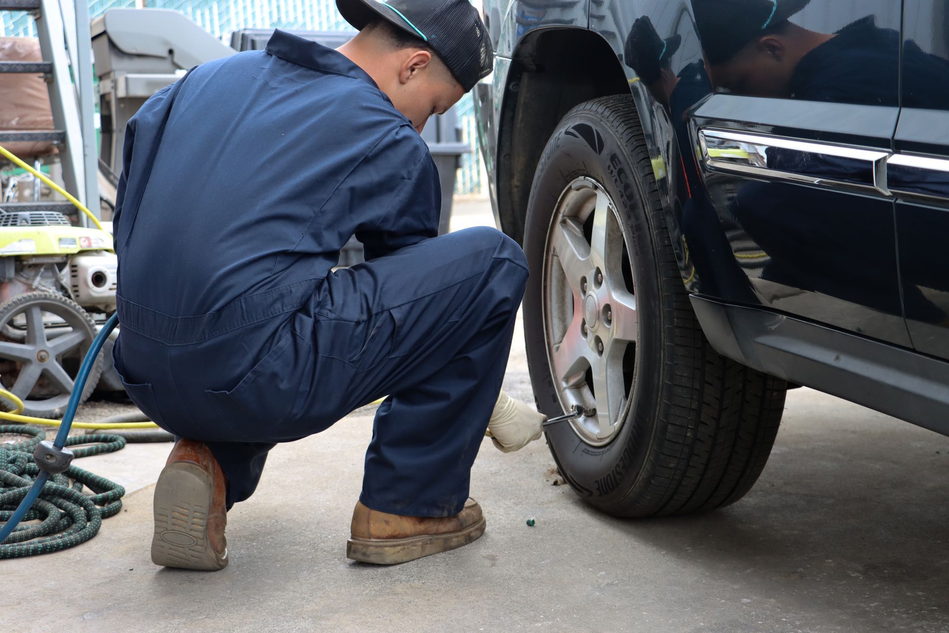 A man is kneeling down to change a tire on a car