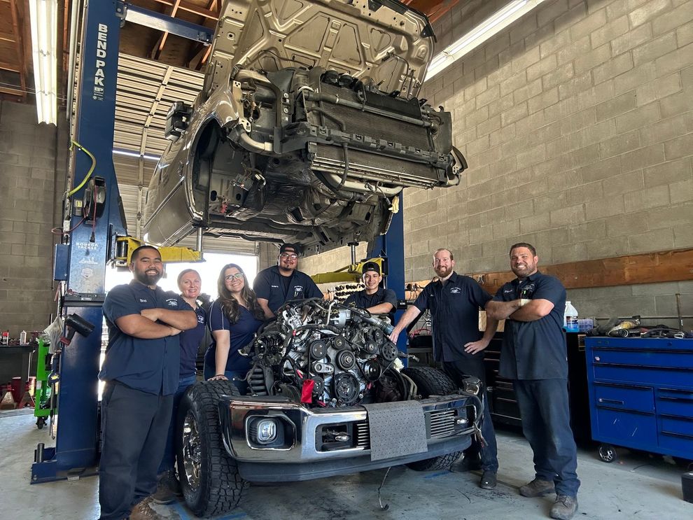 Group photo of bowman's auto repair team under a lifted car