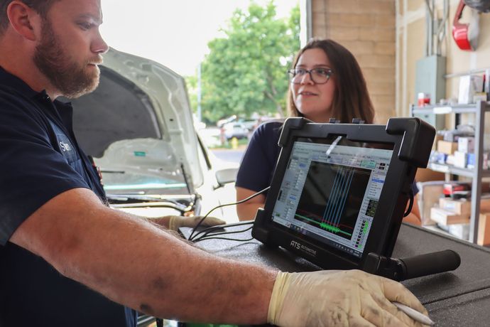 A man and a woman are looking at a tablet in a garage.