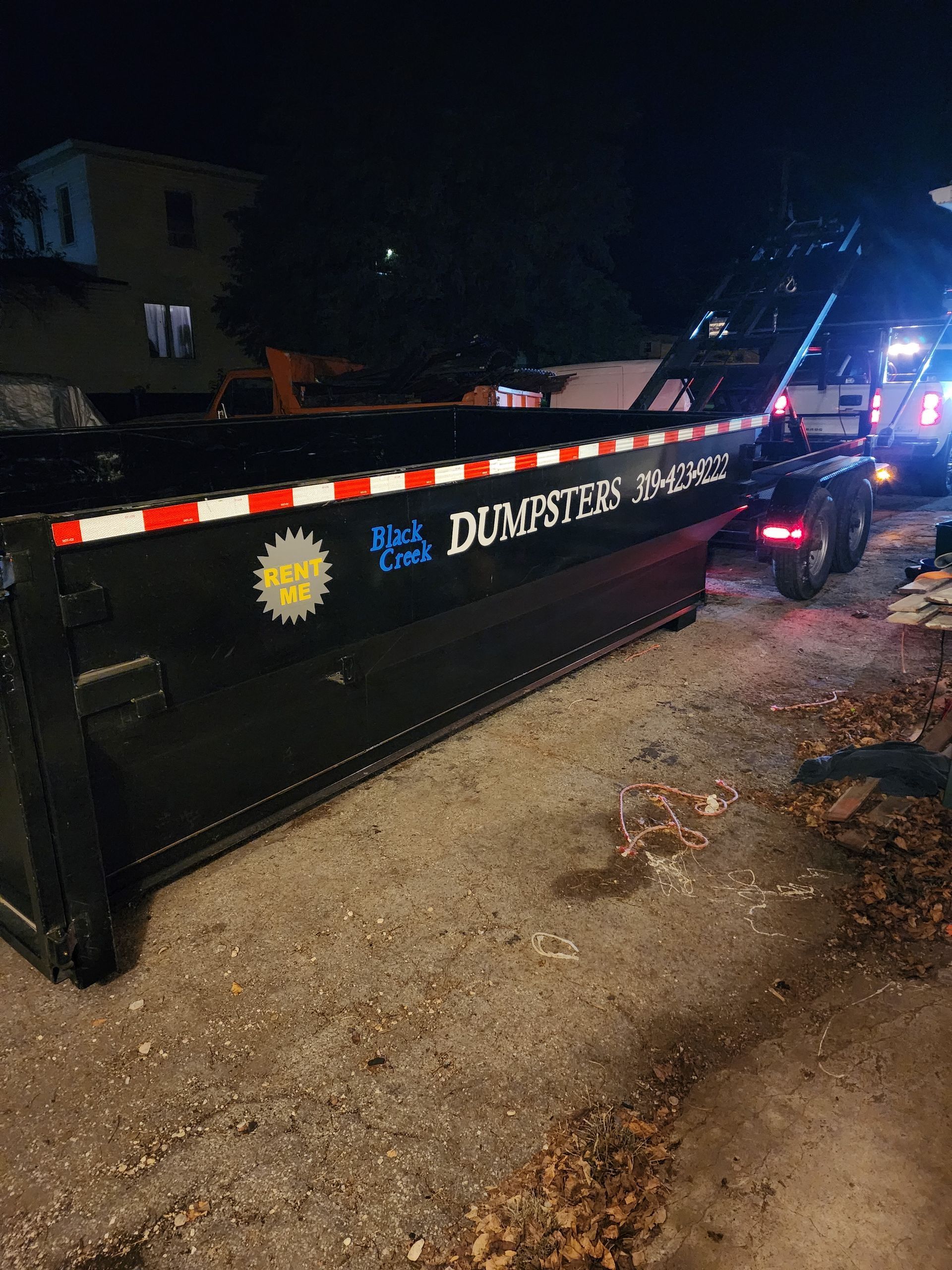 Black dumpster on a truck at night.
